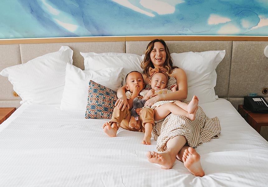 A mother and two children relaxing out on a kingsized bed.